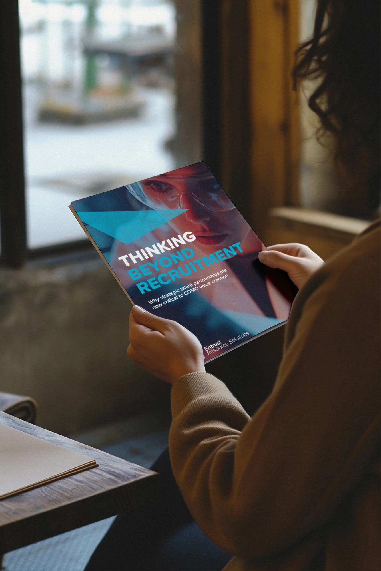 A reader holding the Thinking Beyond Recruitment insights paper from Entrust Resource Solutions